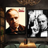 A framed black and white portrait of Marlon Brando as The Godfather hanging on a dark wall.