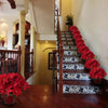 A staircase decorated with a vibrant red poinsettia arrangement on the railing and steps.