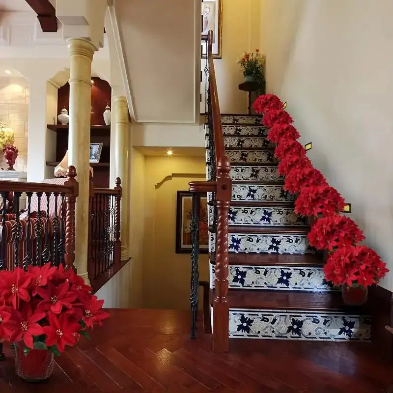 A staircase decorated with a vibrant red poinsettia arrangement on the railing and steps.