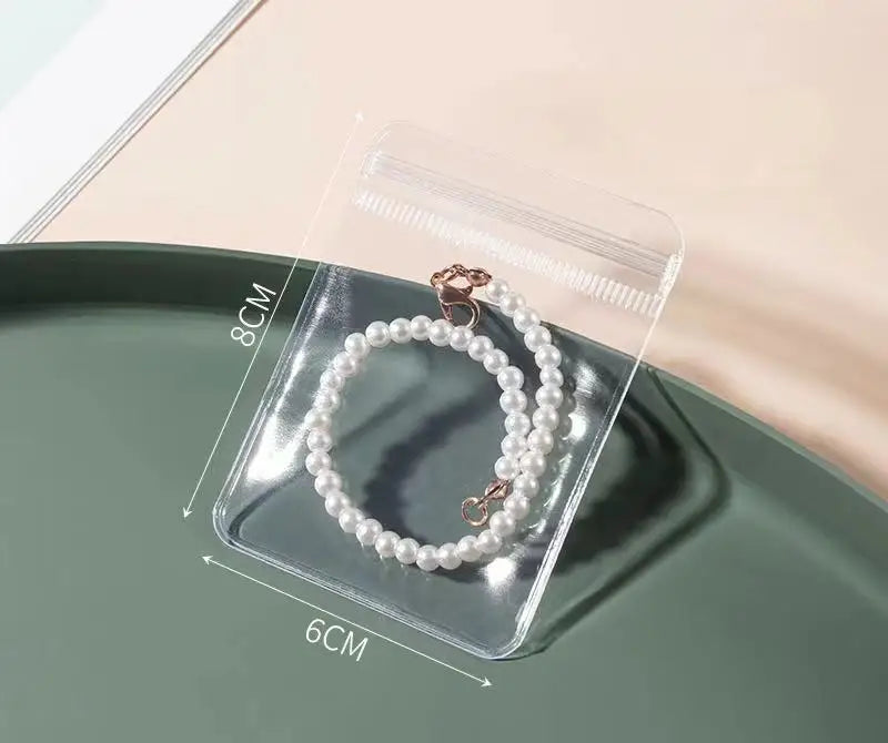 A clear plastic storage bag holds a pearl necklace on a green tray.