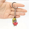 A silver acrylic keychain featuring a cute yellow banana cat with a red heart.