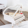 A white hand-crank music box featuring a ballerina with a spinning top, displayed on a wooden surface.