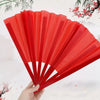 A hand holds open a red Tai Chi performance fan made of durable plastic ribs.