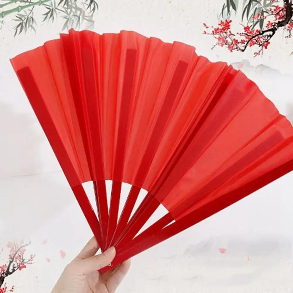 A hand holds open a red Tai Chi performance fan made of durable plastic ribs.