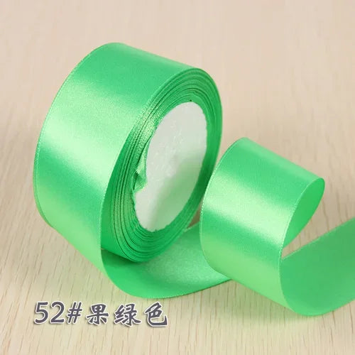 A roll of bright green silk satin ribbon used for gift wrapping and craft projects.