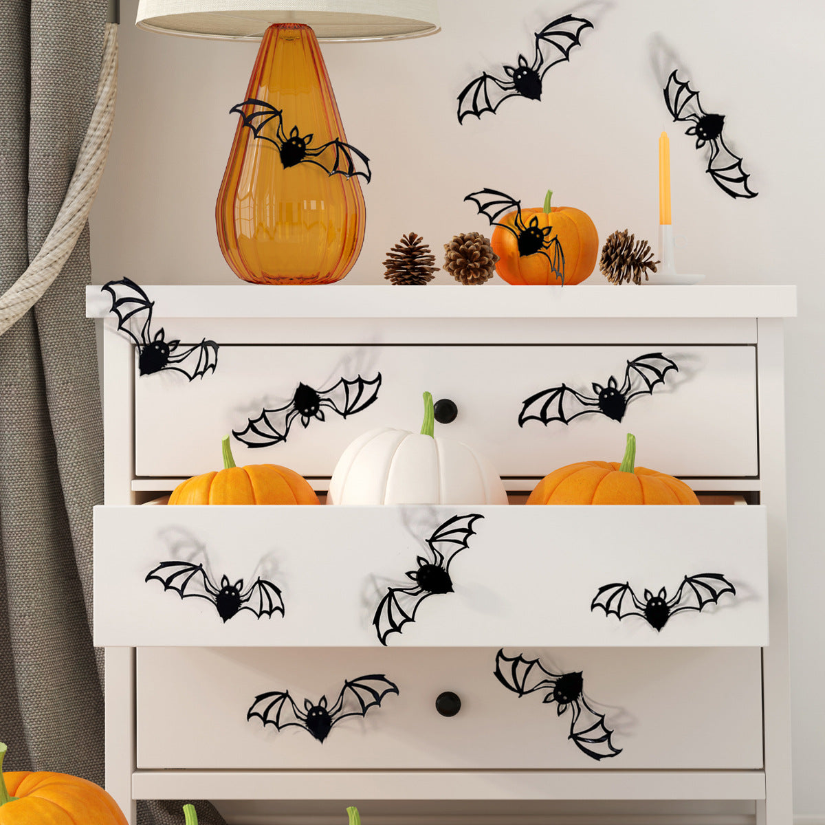 A display featuring various black bat wall decals and an orange glass bottle on a white shelf.
