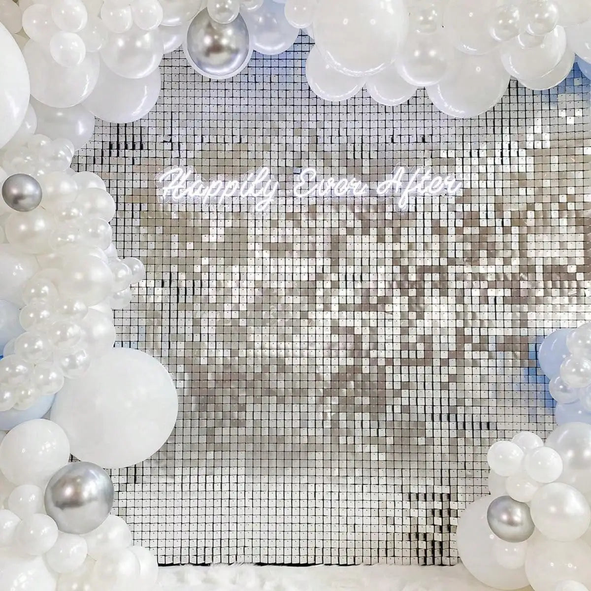 A silver and white sequin glitter party backdrop featuring round and clustered pearl-like decorations.