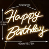 A glowing neon sign shaped like Happy Birthday is hanging against a dark background.