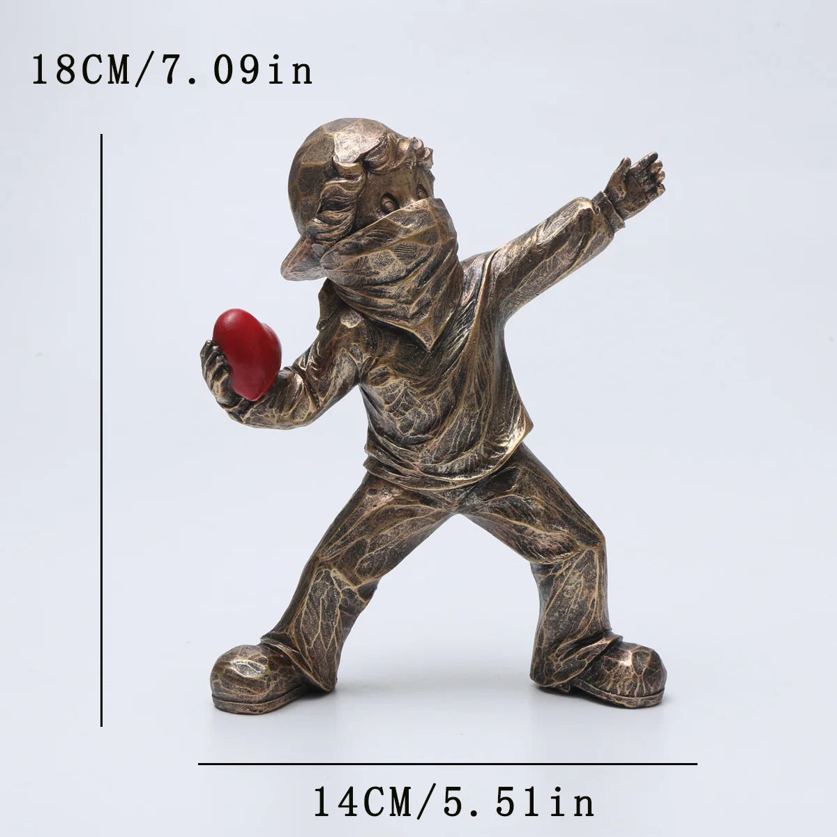 A bronze-colored resin sculpture of a figure throwing a red ball.