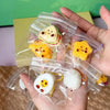 A hand holds several clear plastic pouches containing cute cartoon food squeeze toys like egg and toast.