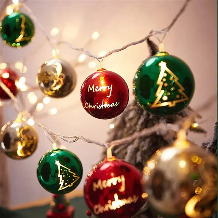 A festive holiday decoration featuring green and red ornaments hanging from fairy lights.