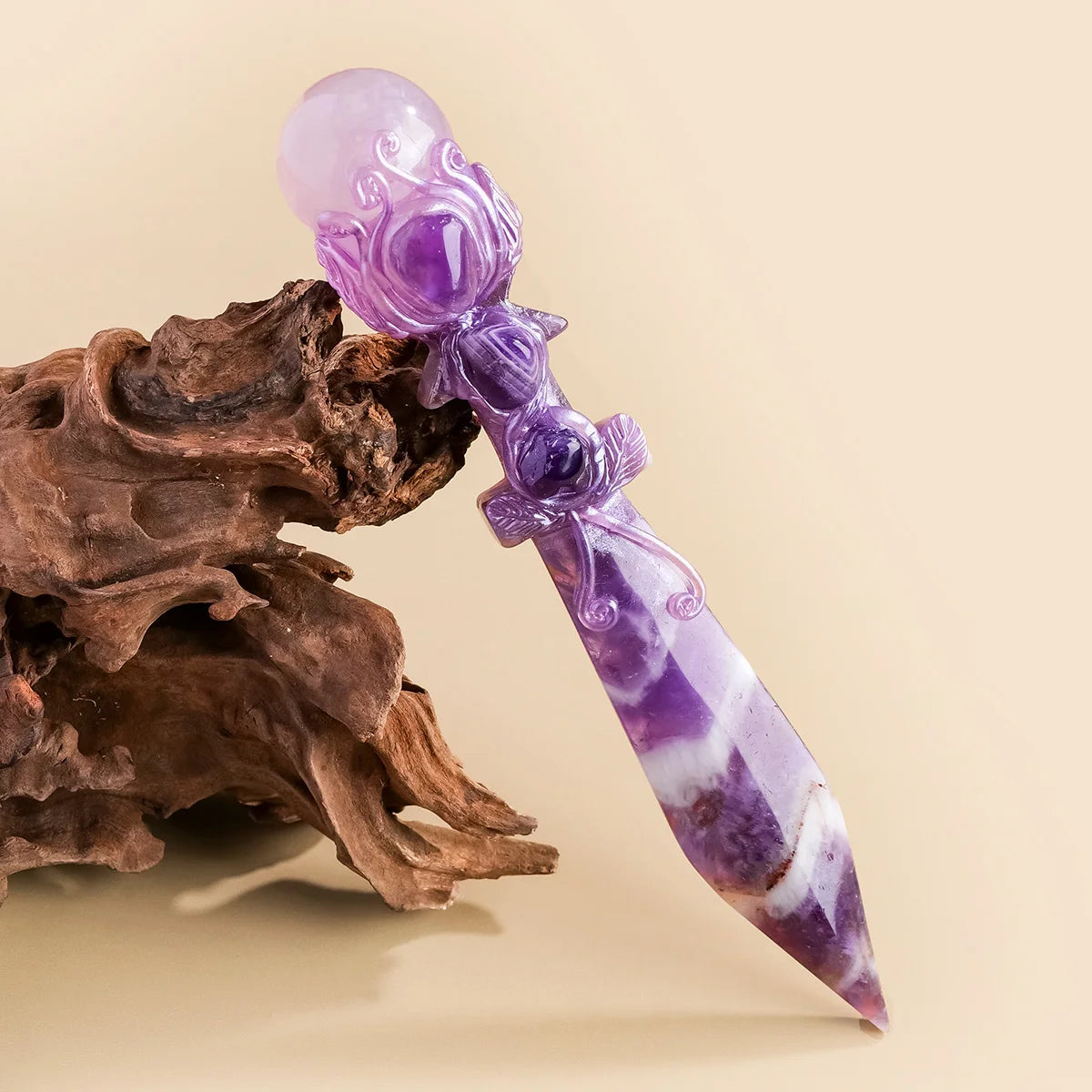 A long, tapered crystal point featuring purple amethyst and white patterns, resting on a piece of driftwood.