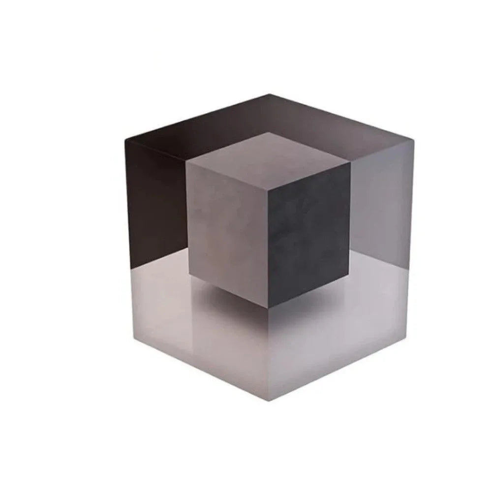 A dark gray cube with a translucent, reflective surface, showing an optical illusion pattern.