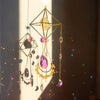 A hanging crystal sun catcher featuring geometric gold wirework and colorful gemstone beads.
