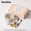 A box containing natural crystal fragments bonded with resin, along with wooden sticks and a gold dropper.