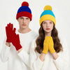 A model wearing a festive knitted beanie and gloves set featuring red, blue, and yellow colors.