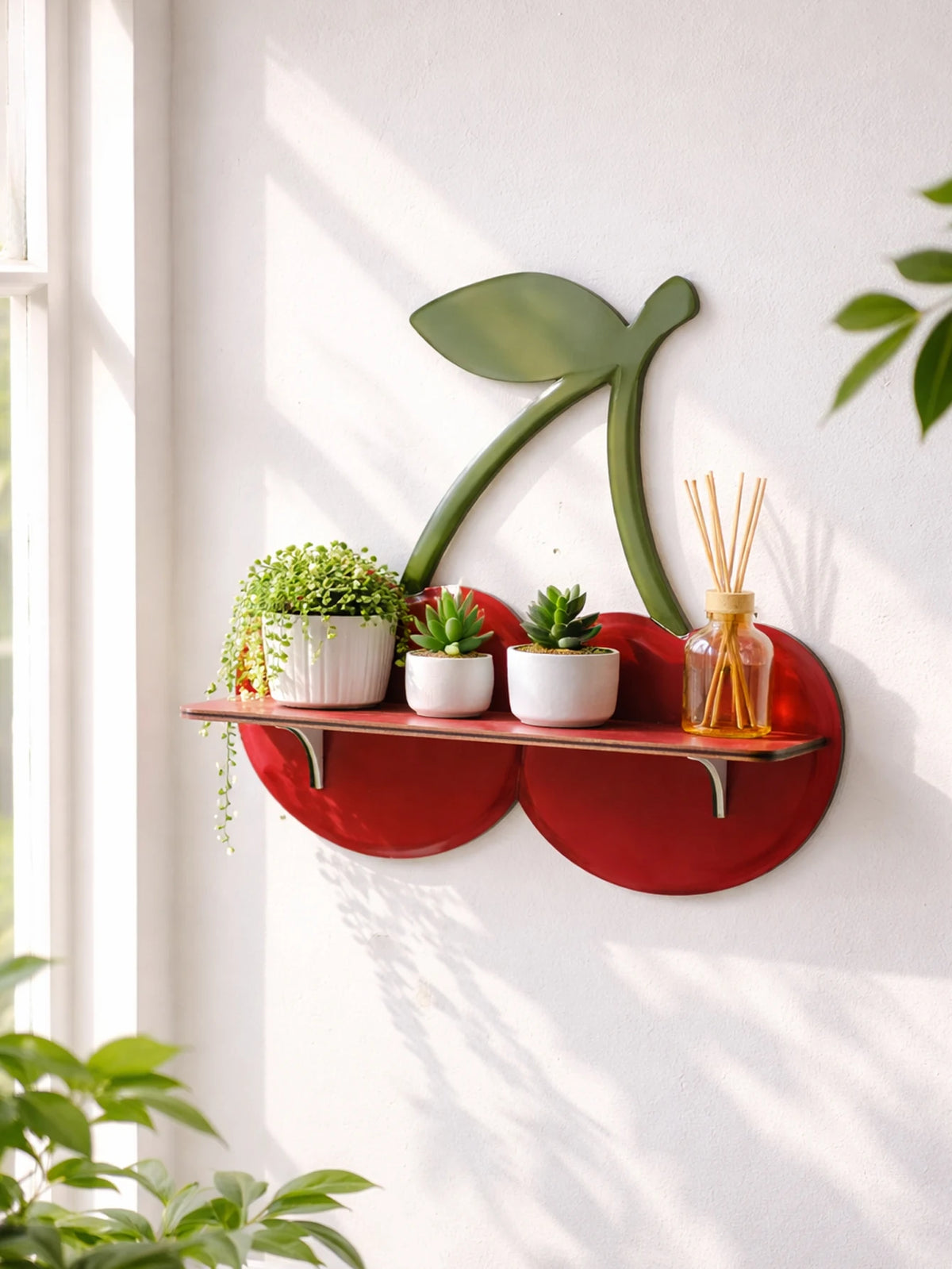 A red wooden wall shelf holds potted plants and a glass jar with thin wooden sticks.