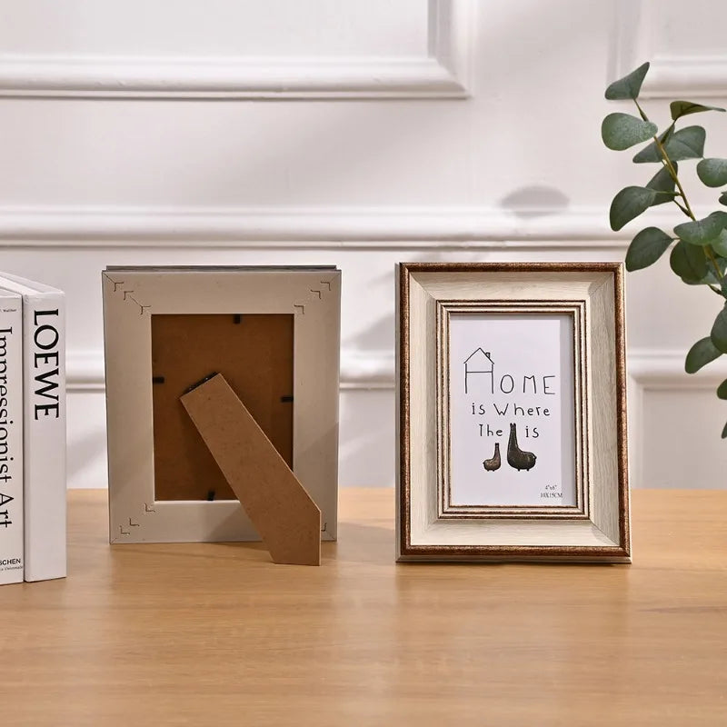 A wooden photo frame with a light gray border and a piece of natural wood inside, displayed on a wooden table.