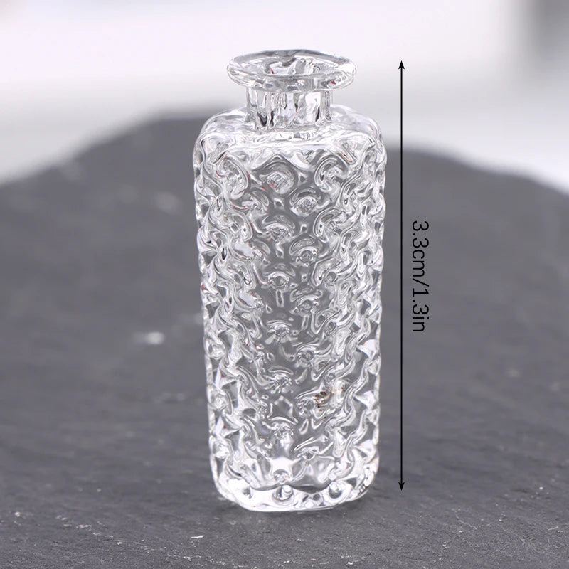 Clear glass miniature dollhouse vase and wine bottle set with a stopper, shown against a dark surface.
