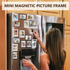 A woman is placing a magnetic picture frame onto the door of a refrigerator displaying several framed photos.