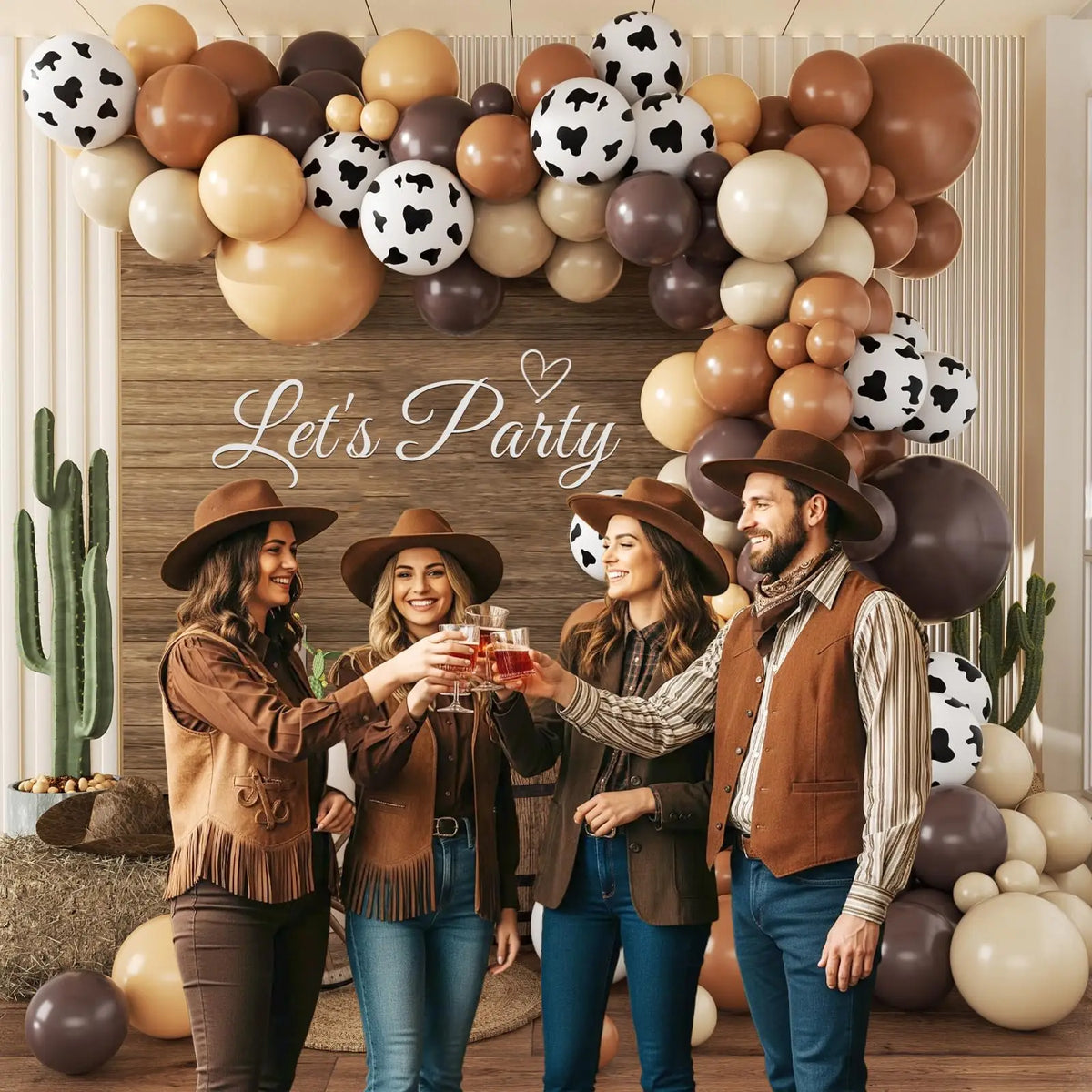 Una pareja está frente a una instalación de globos con temática western en colores marrón, beige y negro.