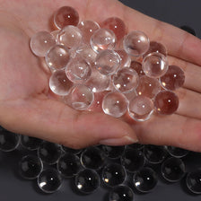A hand holds a cluster of translucent pink and reddish-colored acrylic round beads for crafts and decor.