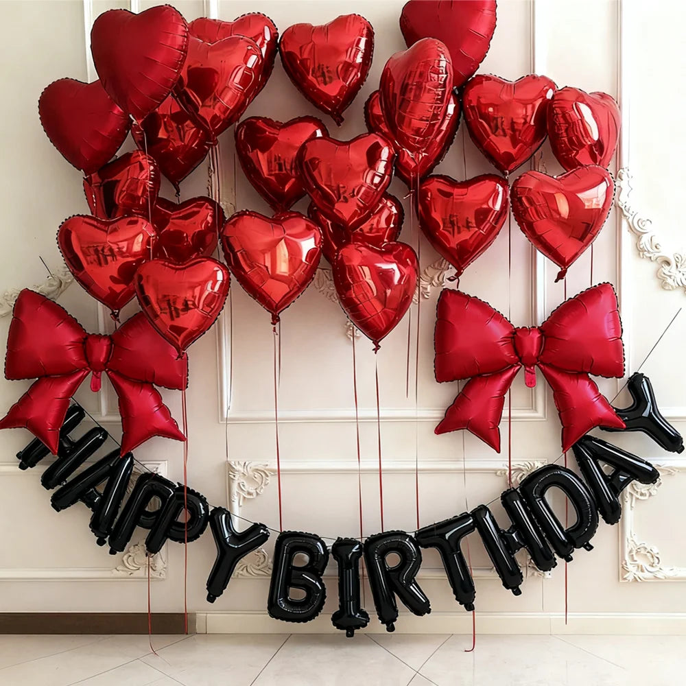 A garland of black heart balloons spelling out HAPPY BIRTHDAY against a white wall.