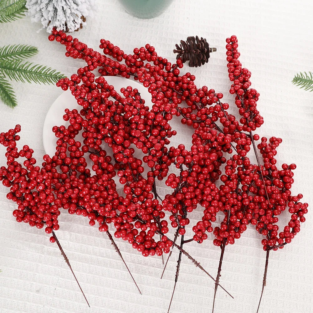 A cluster of artificial red holly berry stems used for Christmas decoration on a white fabric background.