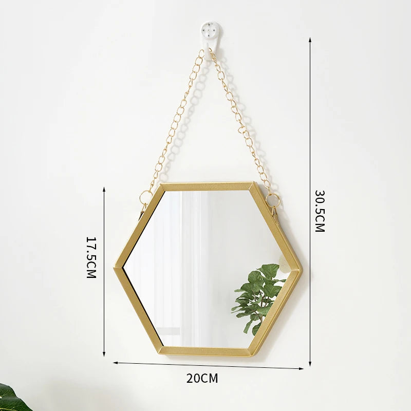A gold-framed hexagon decorative wall mirror hanging by a chain.