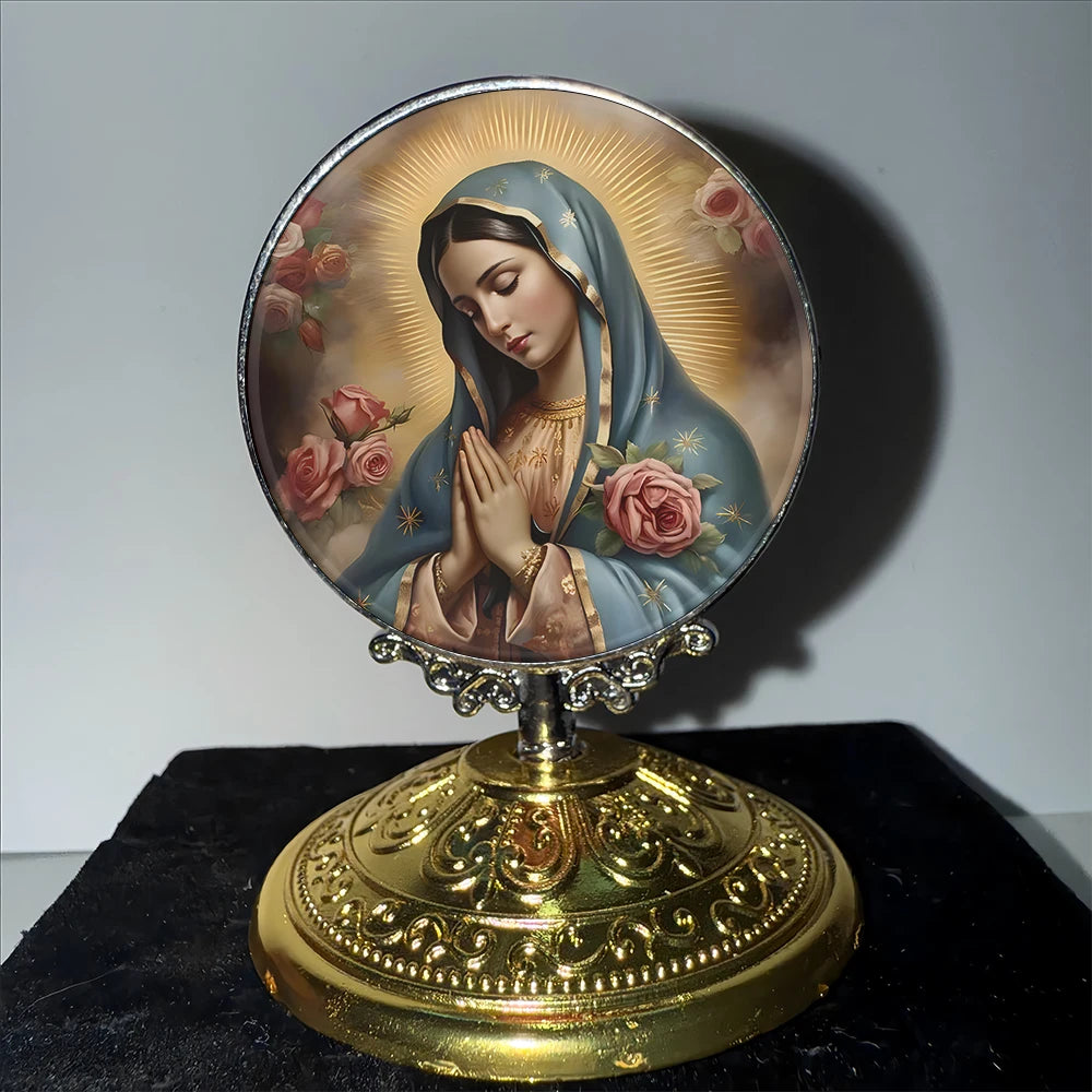 A round religious medal featuring the Virgin Mary with hands clasped in prayer, set on a golden base.