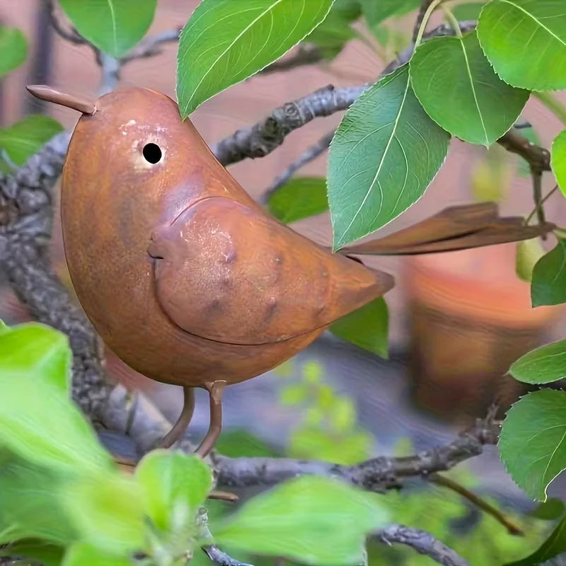 A small brown bird sculpture perched on a tree branch amidst green leaves.