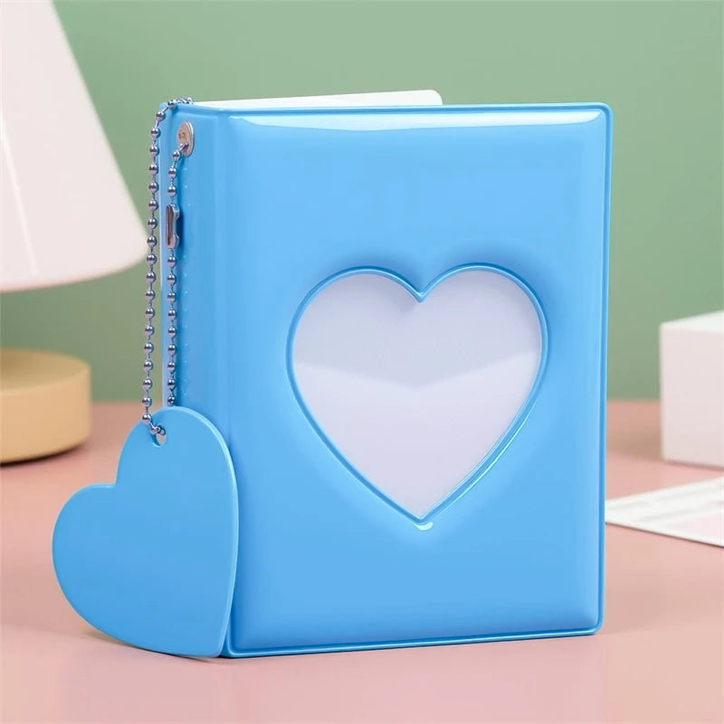 A light blue candy heart window photocard album with a silver chain attached.