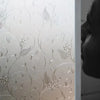 Close-up of frosted electrostatic window film with delicate floral and vine patterns applied to glass.