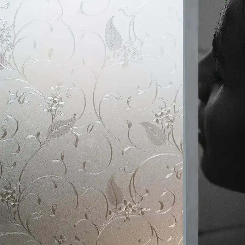 Close-up of frosted electrostatic window film with delicate floral and vine patterns applied to glass.