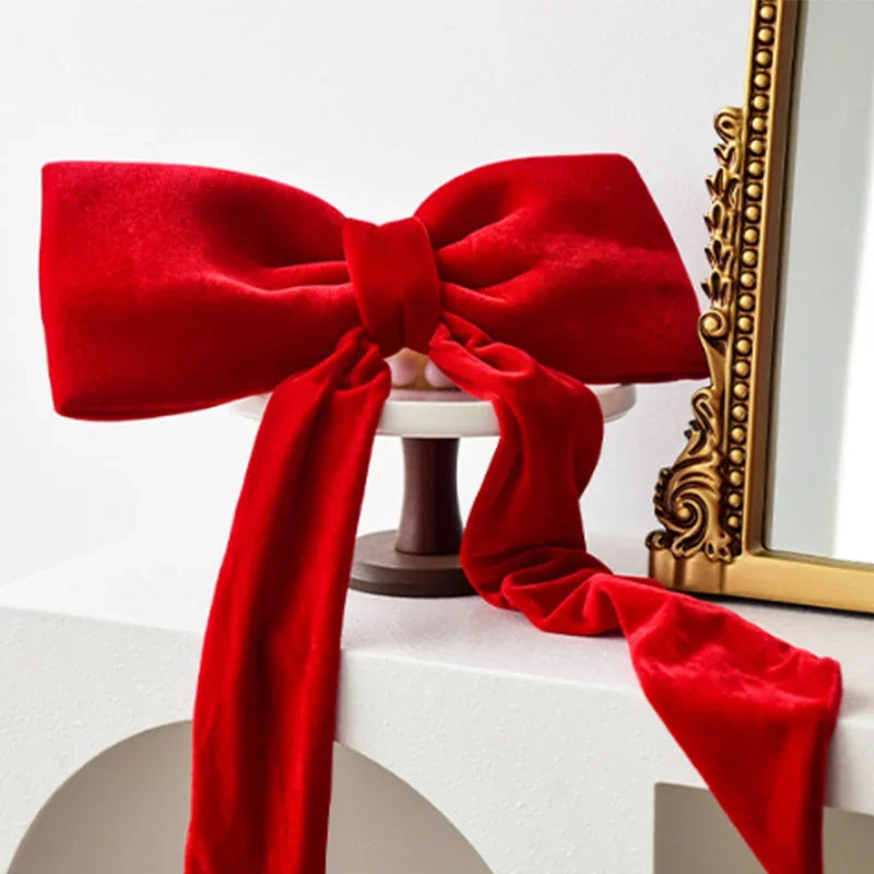 A vibrant red velvet bow tied around a white ornament, displayed on a white surface.