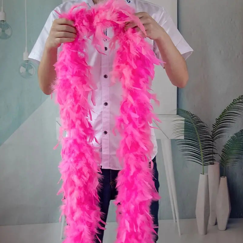 A person is holding a bright pink natural turkey feather boa for costumes and crafts.