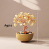 A handcrafted agate crystal tree with a copper wire base sits in a bowl on a neutral background.
