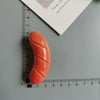 An orange, elongated food-shaped magnet is shown next to a ruler.