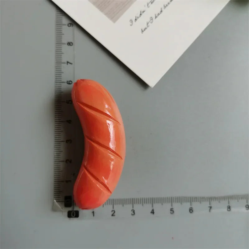 An orange, elongated food-shaped magnet is shown next to a ruler.