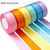 A roll of satin silk ribbon in a rainbow color spectrum, showing various shades of pink, orange, yellow, and blue.