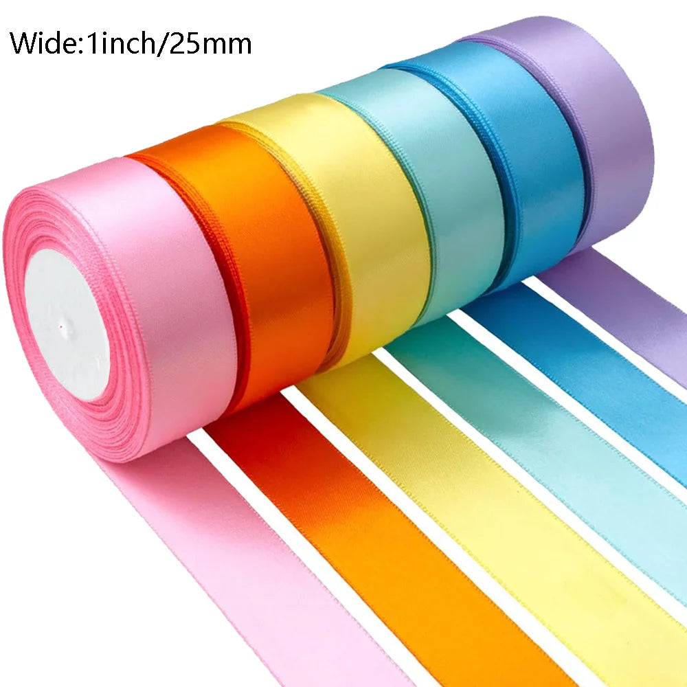 A roll of satin silk ribbon in a rainbow color spectrum, showing various shades of pink, orange, yellow, and blue.