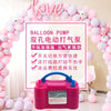 A pink electric balloon pump is displayed in front of a heart-shaped balloon arch decorated with pink and white balloons.