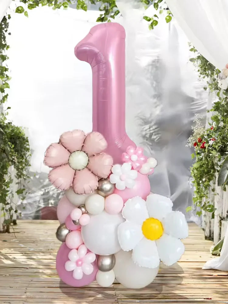 A pink pillar balloon set shaped like the number one decorated with white and pink floral balloons in a bright, airy setting.