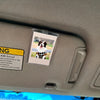 A clear acrylic photo clip showing a dog in a black and white checkered outfit on a car interior panel.