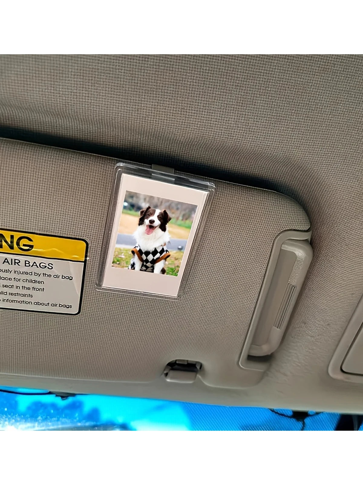 A clear acrylic photo clip showing a dog in a black and white checkered outfit on a car interior panel.