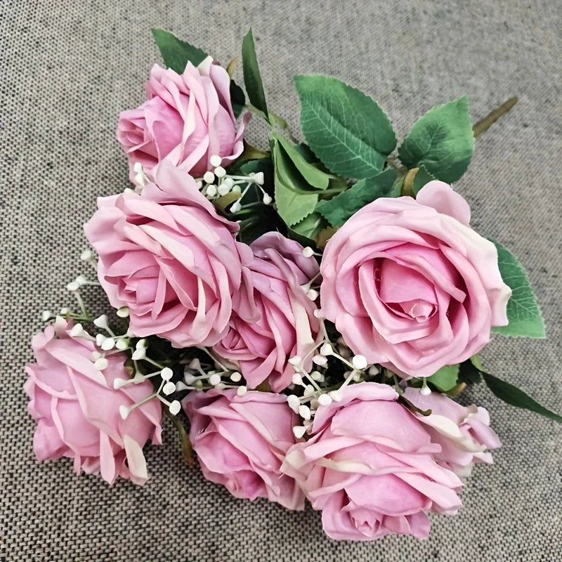 A bouquet of pink roses and green leaves arranged on a gray fabric background.