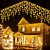 Exterior house decorated with warm yellow string lights and Christmas lights draped across the roof and windows.