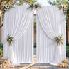 White pleated fabric backdrop curtains framing an entryway decorated with floral arrangements and candles.