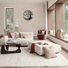 A modern living room featuring a white sofa, accent pillows, and a dark glass coffee table in front of a light wall with a bl