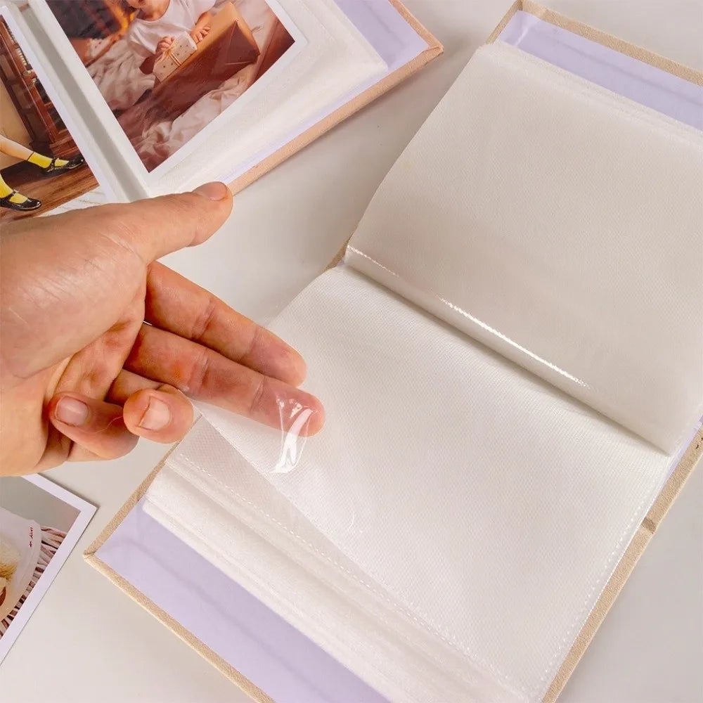 A hand is opening a laminated photo album with clear pockets to view photos.